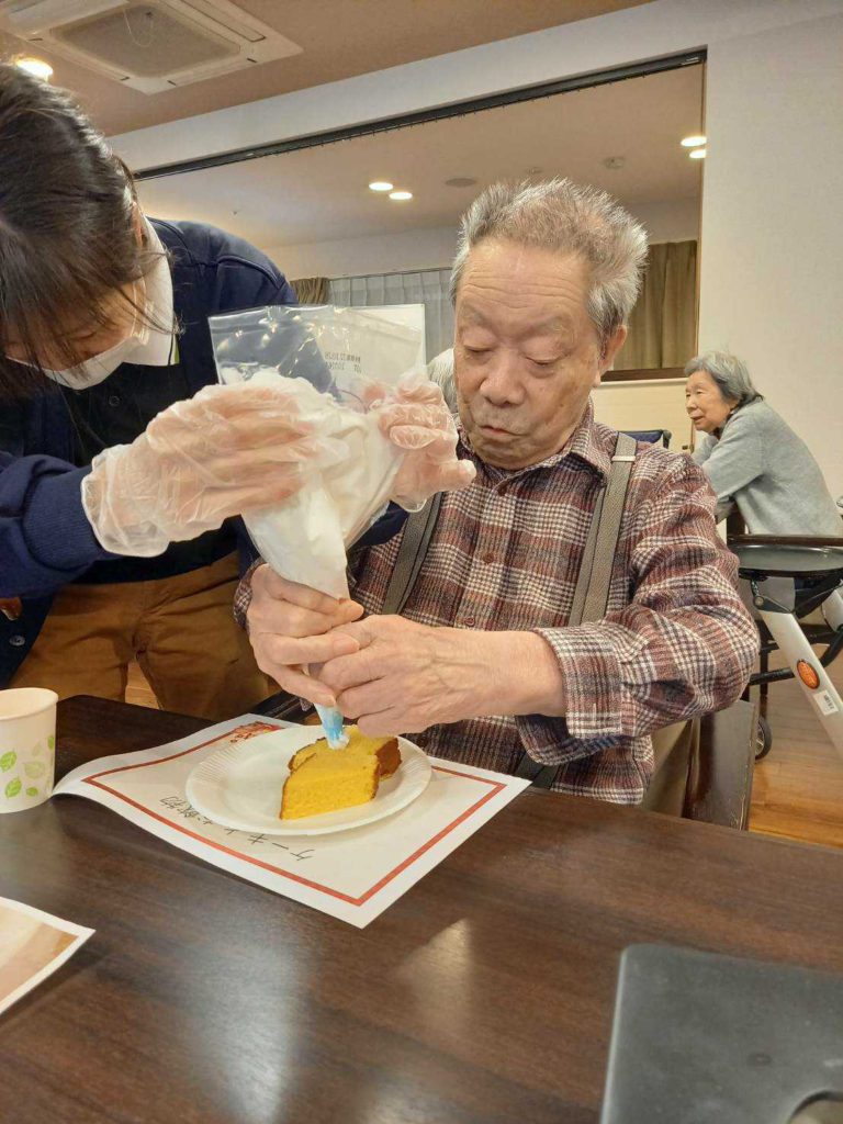 カステラに生クリームをトッピングする男性